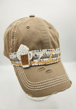 Load image into Gallery viewer, A distressed khaki baseball cap with white contrast stitching, featuring a decorative beaded band around the crown and a small beaded beer mug ornament on the side, displayed on a white mannequin head against a light gray background.