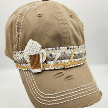 Load image into Gallery viewer, A distressed khaki baseball cap with white contrast stitching, featuring a decorative beaded band around the crown and a small beaded beer mug ornament on the side, displayed on a white mannequin head against a light gray background.
