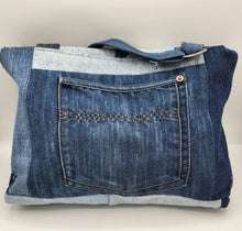 Load image into Gallery viewer, Shop this eco-friendly upcycled denim bag, handcrafted with a patchwork design, adjustable strap, and unique floral detail. Sustainable fashion made from repurposed jeans.