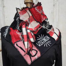 Load image into Gallery viewer, A red, white, and black patchwork cowl scarf with fringe details and a black square patch embroidered with 'WISCONSIN' in white, displayed on a black mannequin torso against a white wood paneled background.