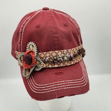 Load image into Gallery viewer, A distressed maroon baseball cap with white contrast stitching, featuring a decorative woven band and a large floral embellishment on the side, displayed on a white mannequin head against a light gray background.