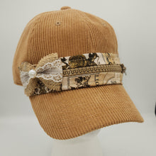 Load image into Gallery viewer, Add a touch of vintage charm to your everyday style with this one-of-a-kind embellished corduroy baseball cap. Crafted in a warm camel/tan corduroy, this cap features a beautifully layered band made from upcycled vintage-inspired fabric, antique-look zipper trim, burlap, delicate lace, and a sweet pearl accent.

