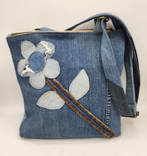 Load image into Gallery viewer, Shop this one-of-a-kind handmade upcycled denim tote bag featuring a floral appliqué design, adjustable strap, and zippered closure. Sustainable, stylish, and perfect for everyday use.
