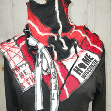 Load image into Gallery viewer, A black knit mock neck sweater scarf displayed on a mannequin torso, featuring a large red and white patchwork scarf with 'Home of Wisconsin' and 'Wash' text tied around the neck.

