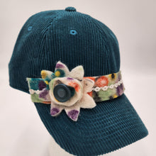 Load image into Gallery viewer, A dark teal corduroy baseball cap with a colorful floral felt headband and a central black button, displayed on a white mannequin head against a light gray background.

