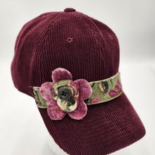 Load image into Gallery viewer, burgundy corduroy cap. The rich wine-colored corduroy fabric gives the hat a soft, textured look, while the decorative floral band adds a beautiful handcrafted touch.

The standout felted flower features layers of coordinating burgundy and green tones, finished with a classic button center. The floral fabric band wraps around the cap for an artistic, one-of-a-kind look.
