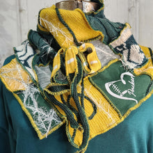 Load image into Gallery viewer, Green bay packers handmade scarf, A handmade knit scarf with a football theme, featuring green and yellow stripes, white yarn details, and a white script logo on a green panel, displayed on a mannequin torso.
